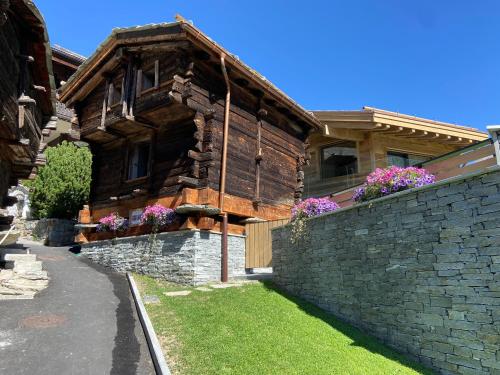 采尔马特Chalet Coral und Zermatter Stadel的一座带石墙的大型木制房屋