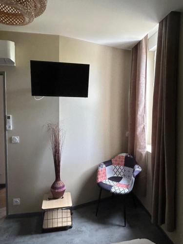 苏亚克Les tilleuls的配有电视、椅子和花瓶的房间