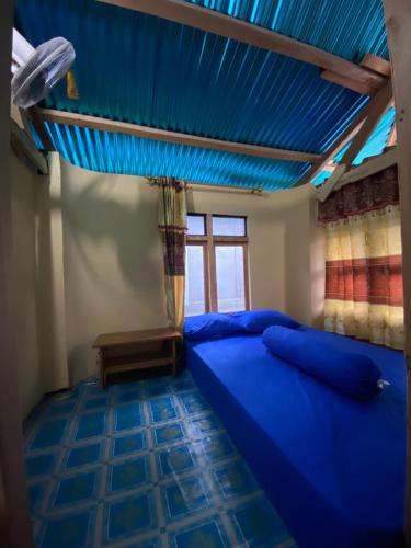 KomodoDua Putri Komodo Homestay的一间卧室设有蓝色的床和蓝色的天花板