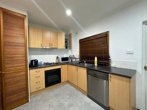 悉尼Remarkable 2 Bedroom House at the Centre of Darlinghurst的厨房配有木制橱柜和黑色台面
