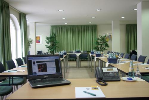 拉德博伊尔高德纳安克酒店的一间会议室,配有桌子、笔记本电脑和电话