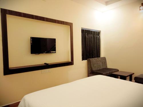 埃尔加德R Hotels By Suraj Residency Yercaud的一间卧室配有一张床、镜子和椅子