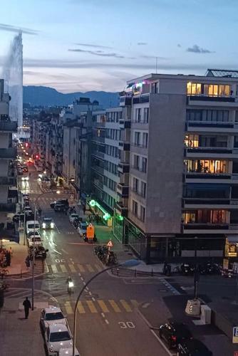 日内瓦Espacioso apartamento的一条城市街道,晚上有汽车和建筑