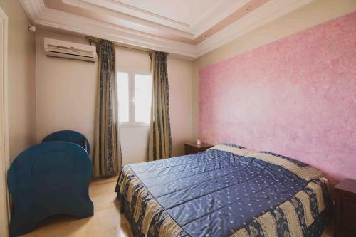塔格梅斯Menzel Troguet, Dream House in Djerba的一间卧室设有蓝色的床和粉红色的墙壁