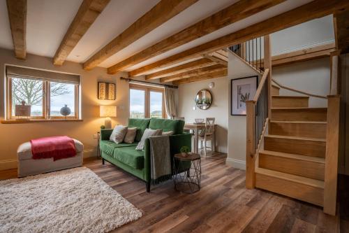 埃文河畔斯特拉特福Piglet's Hideaway的客厅设有绿色沙发和楼梯。