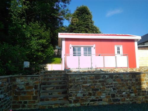 巴特马林贝格Ferienhaus in Bad Marienberg Westerwald mit Grill und Terrasse的砖墙顶上的粉红色小房子