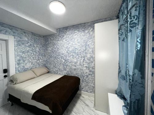 布鲁克林3 bedrooms in Modern Brooklyn home, Close to J train的一间配备有床铺的卧室,位于一间蓝色壁纸的房间
