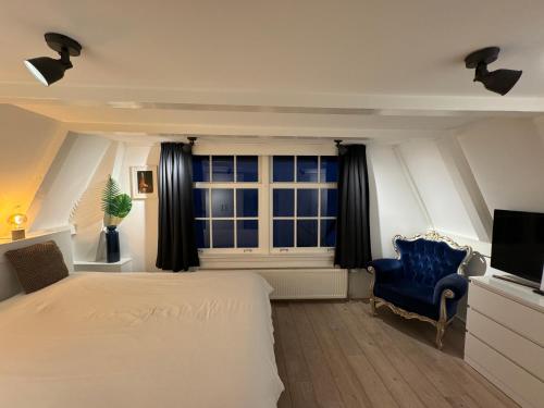 阿姆斯特丹九街住宿加早餐旅馆的一间卧室配有一张床、一把蓝椅和一个窗户。
