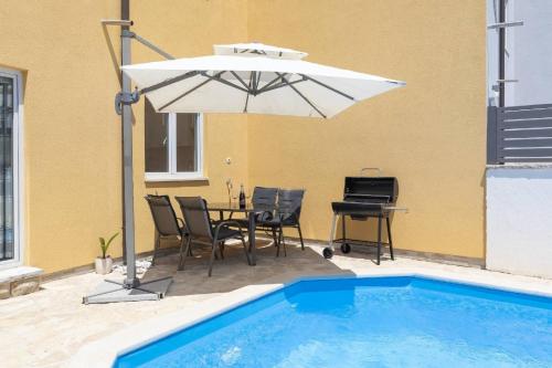 罗波里卡Villa Kostre的一个带桌子和遮阳伞的庭院,毗邻一个游泳池