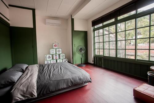 高雄兴华居室的一间带绿色墙壁的卧室和一张带风扇的床