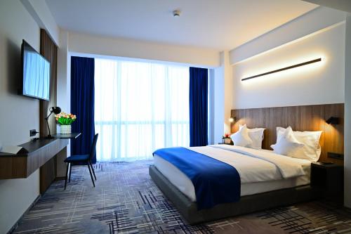 布加勒斯特Hotel Sir Royal的酒店客房设有一张床、一张书桌和窗户。