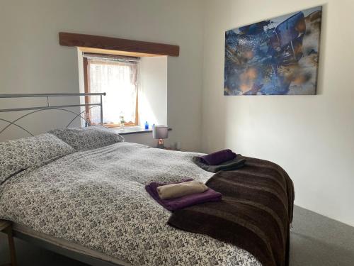 朗塞斯顿Rosehip Barn的一间卧室配有一张带紫色枕头的床