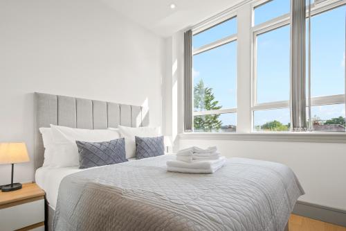 PinnerOne Bedroom Serviced Apartments in Harrow的白色卧室设有一张大床和两个窗户
