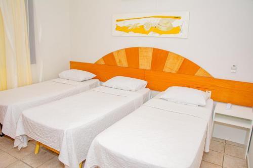 纳塔尔Garbos Soleil Hotel的配有白色床单的客房内的两张床