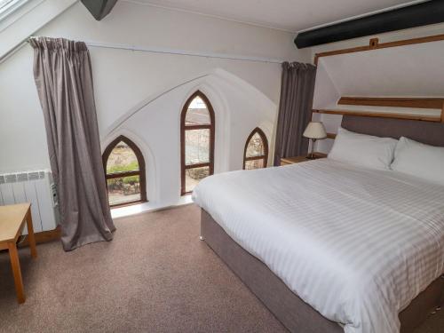 雷文格拉斯Old School Muncaster House的一间卧室设有一张大床和两个窗户。