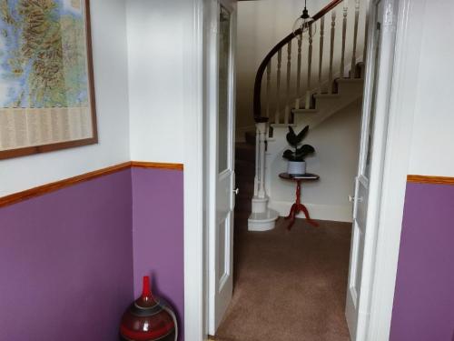 克里安拉利Ferienhaus für 6 Personen ca 100 qm in Crianlarich, Schottland Loch Lomond and the Trossachs Nationalpark的一条拥有紫色和白色墙壁的走廊和楼梯