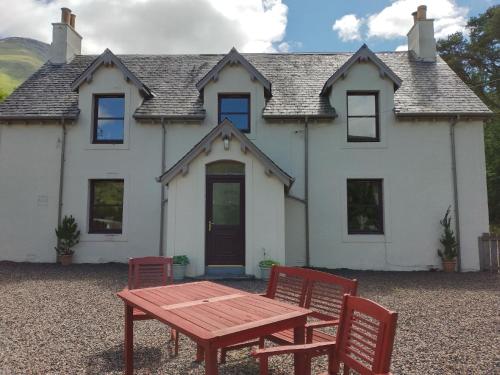 克里安拉利Ferienhaus für 6 Personen ca 100 qm in Crianlarich, Schottland Loch Lomond and the Trossachs Nationalpark的房子前面的一张桌子和椅子