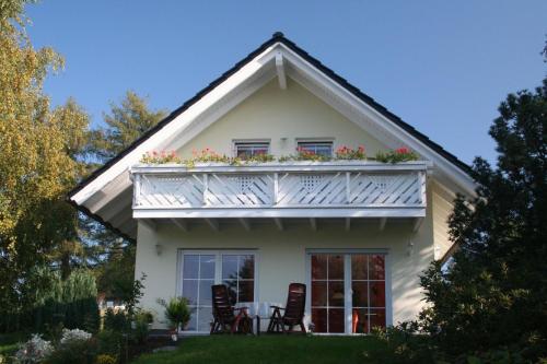 BeerheideFerienhaus Vogtlandresidenz的白色的房子,阳台上放着鲜花