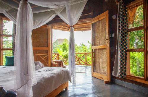 RwinkwavuRutete Eco Lodge的一间卧室设有一张天蓬床和大窗户