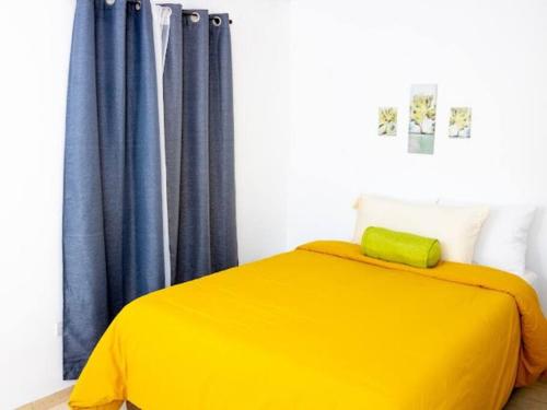 Antiguo CuscatlánCozy Two Bedroom Apartment Near The U.S. Embassy的蓝色窗帘的房间的一张黄色的床