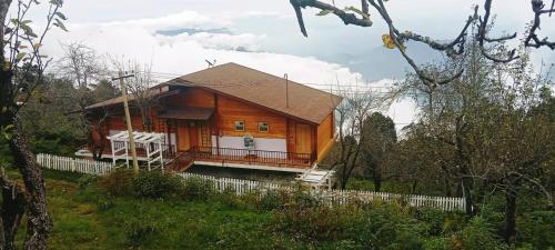 科代卡纳尔Praveen Woodhouse and Homestay Kodaikanal Vattakanal的一座大型木屋,在田野上设有门廊