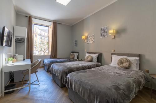 罗马ESQUILINO HARMONY GUESTHOUSE - close to COLOSSEUM的酒店客房设有两张床、一张书桌和一个窗户。