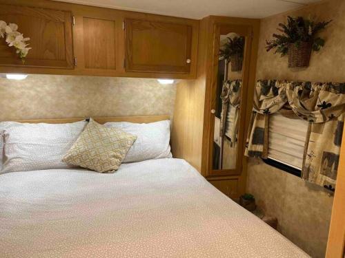 迈阿密WARM AND COZY RV 3的一间卧室配有一张带白色床单和橱柜的床。