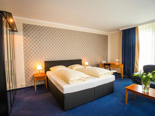 奥斯塔泰Ahauser Land & Golfhotel的一间卧室配有一张带两张桌子和两盏灯的床。