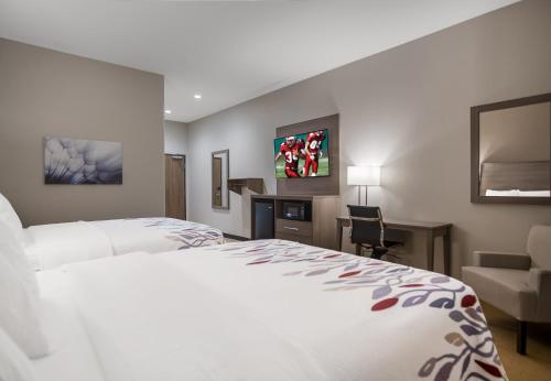 兰开斯特Red Roof Inn Lancaster, TX的酒店客房配有一张床、一张桌子和一把椅子。