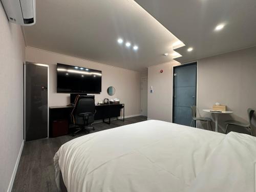 全州市호텔 써밋스테이的一间卧室配有一张床、一张书桌和一台电视。