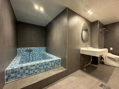 全州市호텔 써밋스테이的浴室设有蓝色瓷砖浴缸和水槽。