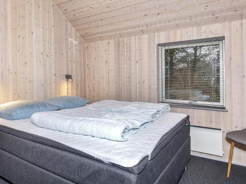 FarsøHoliday home Farsø VIII的木墙客房的一张床位