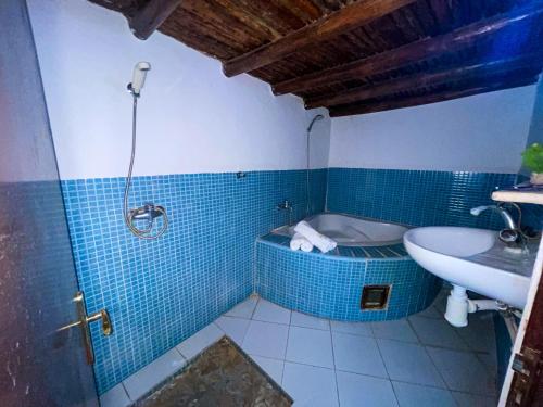阿加迪尔Auberge le Refuge的浴室配有蓝色瓷砖浴缸和水槽。
