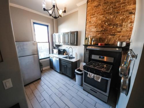 布鲁克林Historic Bushwick, Brooklyn Brownstone Apartment的厨房配有烤箱和砖墙
