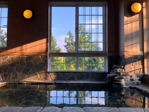 南鱼沼市Koguriyama Sanso - Vacation STAY 14530v的一座带窗户和岩石墙的别墅内的游泳池