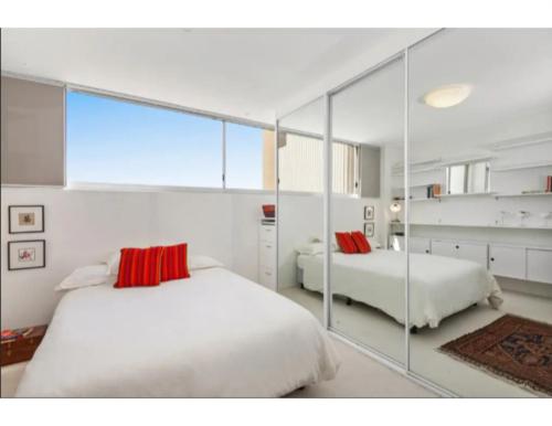 悉尼Beachside Paradise - Ocean Views, Central Position的一间卧室设有两张床和大镜子
