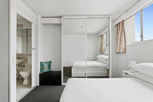 悉尼Apartment with Pool Access, a minute to the Beach的卧室配有白色的床和镜子