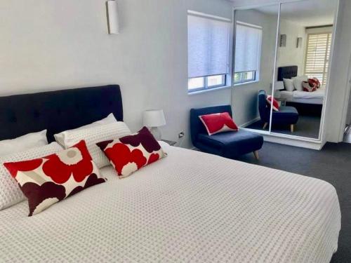 努萨角Absolute Hastings Street Noosa Suite的一间卧室配有一张带红色和白色枕头的大床