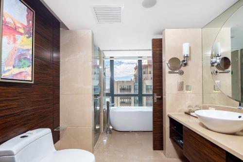 海口海南新燕泰大酒店的带浴缸、卫生间和盥洗盆的浴室
