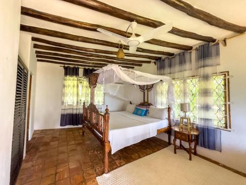 MsambweniSansuri Beach House的一间卧室配有一张床和吊扇