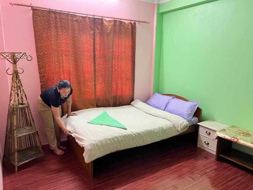 PanepaAraniko homestay的女人在卧室里做床