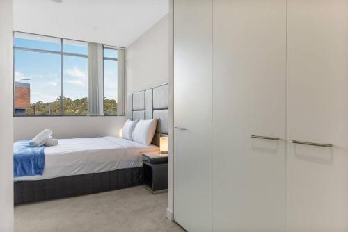 悉尼Two Bedroom Private Apartment In Lane Cove with Parking的一间卧室设有一张床和一个大窗户