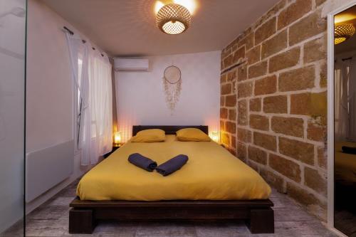 蒙彼利埃Le Chapeau Rouge - Centre Historique - Corum的卧室设有一张大黄床,位于砖墙内