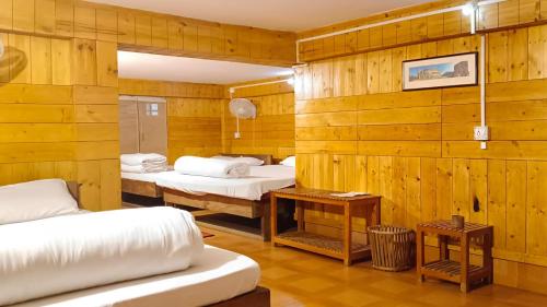 Uttar SimlabariSDD Bamboo Village Resort的木墙客房的两张床