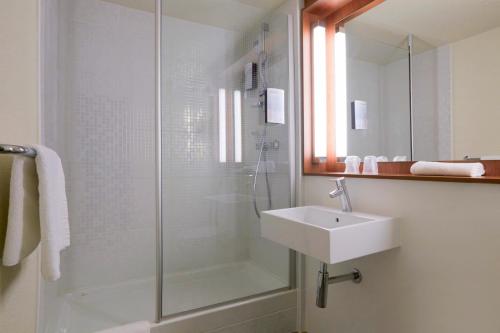 维拉尔钟楼圣艾迪安中央维拉特拉斯酒店的一间带玻璃淋浴和水槽的浴室