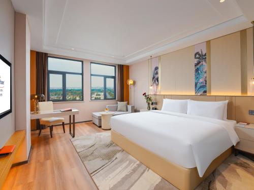 新余新余华侨豪生大酒店的卧室配有一张白色大床和一张书桌