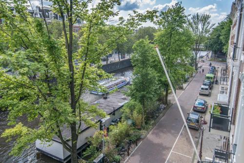 阿姆斯特丹Amstel Corner Hotel的享有河流美景,街道上设有停车位