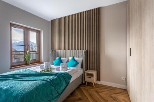 斯克拉斯卡波伦巴Apartament C3 Green Resort z Basenem, Sauną, Jacuzzi - 5D Apartments的一间卧室配有一张带蓝色枕头的床和一扇窗户。
