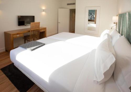 里乌德洛茨·德拉塞尔布拉瓦伊甸园酒店的一张大白色的床,位于带书桌的房间里