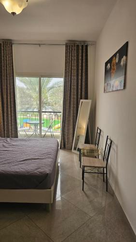 拉斯阿尔卡麦Luxury villa 4 bedroom with pool access的卧室配有一张床和一张桌子及椅子